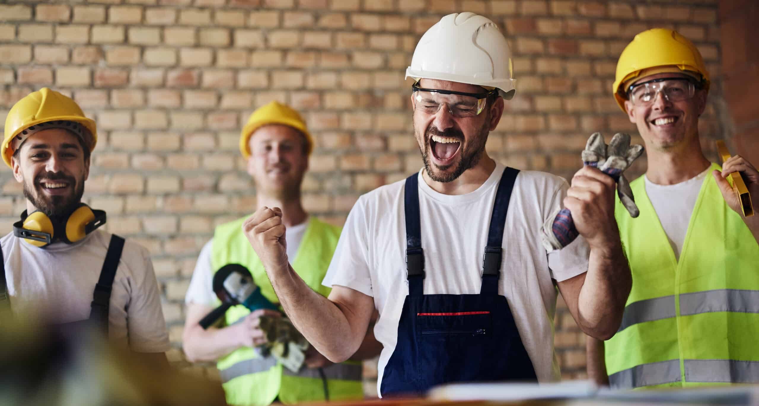 Cheerful worker celebrating success in front of his team at construction site.